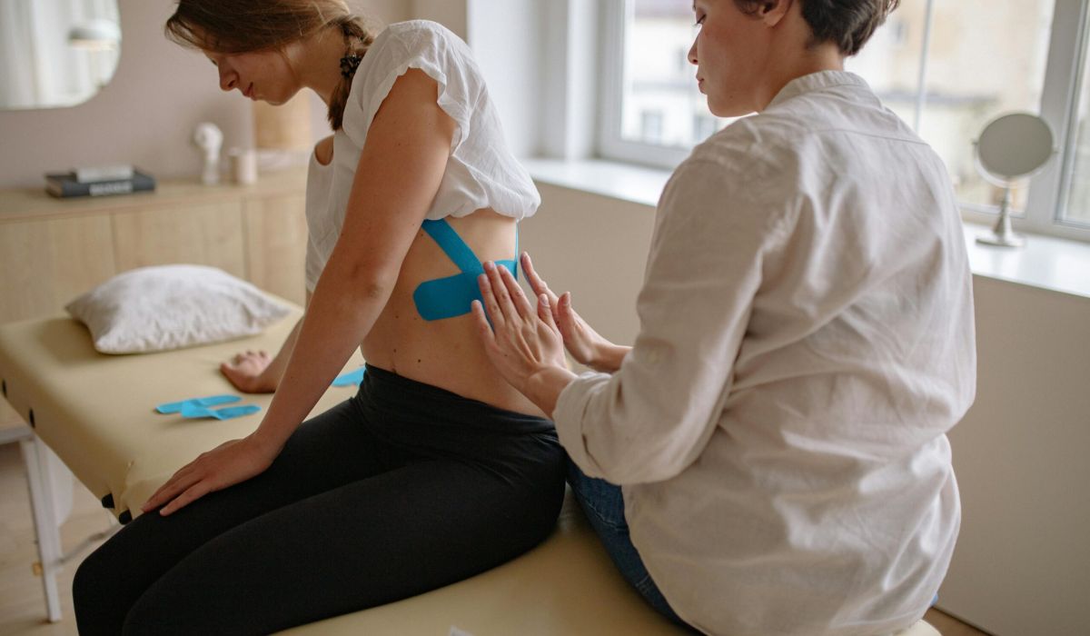 fisioterapeuta poniendo bandas a una mujer en la espalda